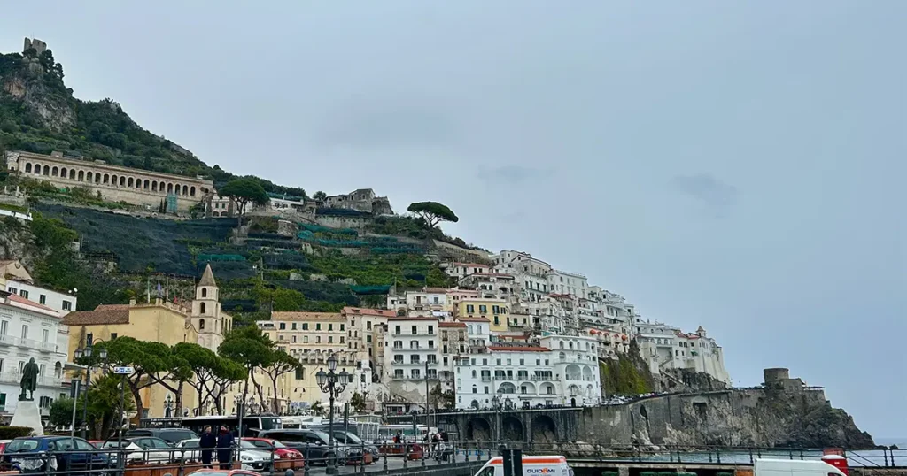 Cliffside view of Amalfi, Italy, with pastel-colored buildings stacked along steep hillsides above the sea