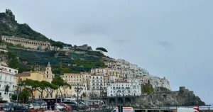 Cliffside view of Amalfi, Italy, with pastel-colored buildings stacked along steep hillsides above the sea