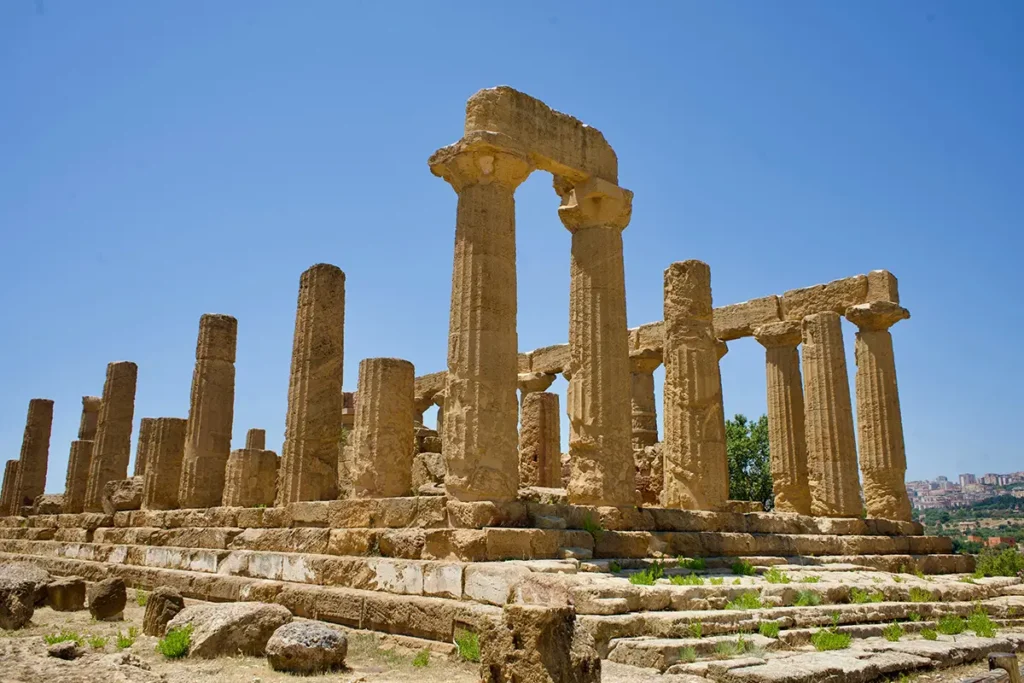 The ancient Greek Temple of Concordia in Agrigento, Sicily, stands well-preserved with its Doric columns under a soft, twilight sky.