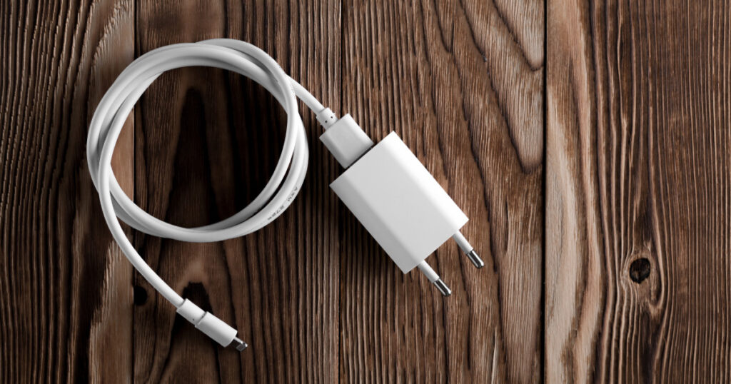 A cell phone charging cable is plugged into a European power adaptor