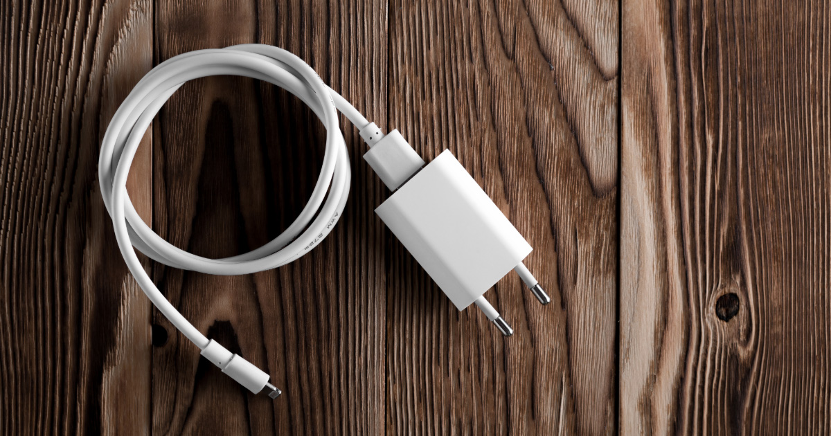 A cell phone charging cable is plugged into a European power adaptor