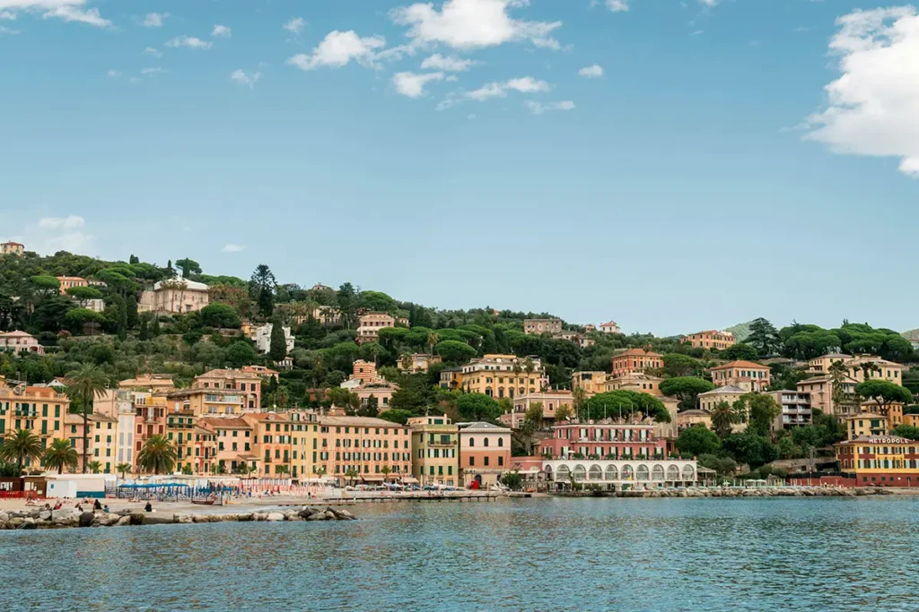 Colorful coastal buildings and palm trees line the harbor front of Santa Margherita Ligure, Italy, overlooking blue water and docked boats.