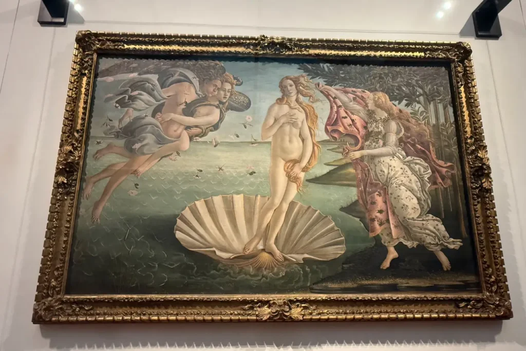 Botticelli's iconic painting "The Birth of Venus" displayed in an ornate gold frame on a gallery wall.
